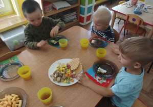 dzieci przy stolikach świętują dzień dziewczynki, na stolikach słodki poczęstunek