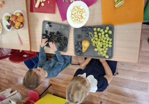 dzieci przy stolikach kroją owoce podczas zajęć kulinarnych