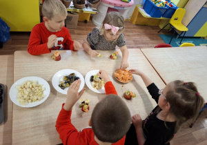 dzieci przy stolikach kroją owoce podczas zajęć kulinarnych