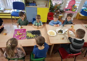 dzieci przy stolikach kroją owoce podczas zajęć kulinarnych