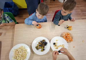 dzieci przy stolikach kroją owoce podczas zajęć kulinarnych