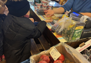 Dziewczynka odbiera resztę pieniędzy za zakupione owoce.