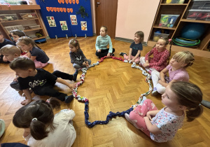 Dzieci siedzą na podłodze i bawią się sigumą.