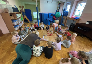 Dzieci siedzą na podłodze i bawią się sigumą.