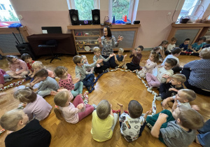 Dzieci siedzą na podłodze i bawią się sigumą.