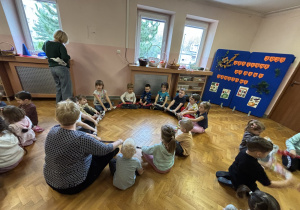 Dzieci siedzą na podłodze i bawią się sigumą.