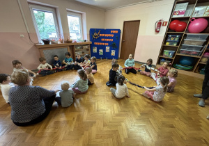 Dzieci siedzą na podłodze i bawią się sigumą.