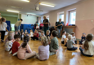 Dzieci siedzą na podłodze i bawią się przy muzyce.