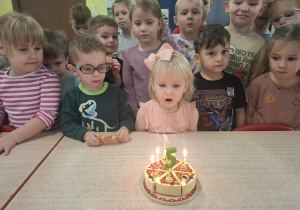 dziewczynka świetuje urodziny, dzieci składają jej życzenia