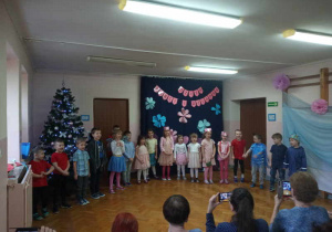 Dzieci na sali gimnastycznej śpiewają piosenkę.