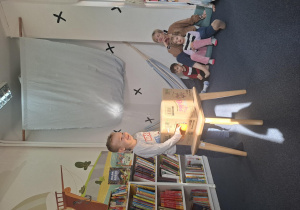 Dzieci siedzą i obserwują chłopca, który świeci latarką.