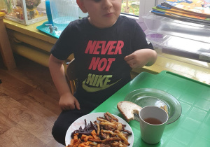 Dzieci siedzą przy stole i degustują frytki, które wykonały.