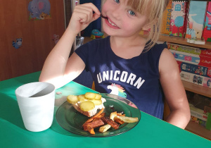 Dzieci siedzą przy stole i degustują frytki, które wykonały.