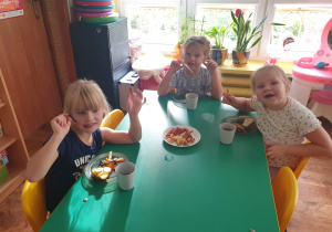 Dzieci siedzą przy stole i degustują frytki, które wykonały.