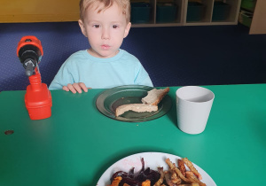 Dzieci siedzą przy stole i degustują frytki, które wykonały.