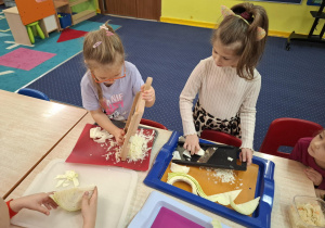 Dzieci szatkują kapustę.