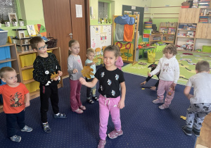 Dzieci tańczą z liśćmi do muzyki.
