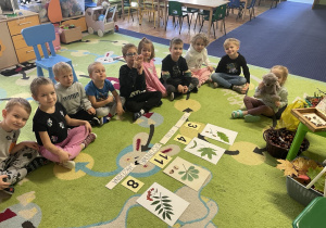 Dzieci siedzą w kole na dywanie.