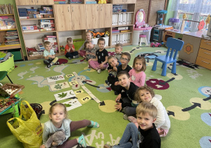 Dzieci siedzą w kole na dywanie.