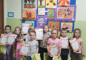 Uczestnicy konkursu wraz z nagrodami na tle swoich prac.