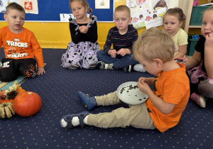 Dzieci siedzą w kole i degustują pestki dyni.