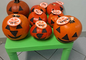 Ozdobione dynie leżą na stoliku.