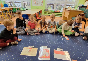 Dzieci siedzą w kole przed nimi leżą symbole Polski.
