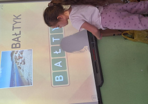 Dziewczynka wykonuje zadanie przy tablicy interaktywnej.