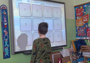 Chłopiec wykonuje zadanie przy tablicy interaktywnej.