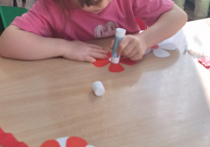 Dzieci siedzą przy stole i wykonują zadanie.