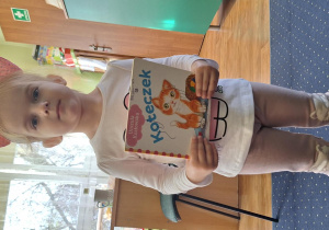 Dziewczynka w przebraniu prezentuje swoją książkę.