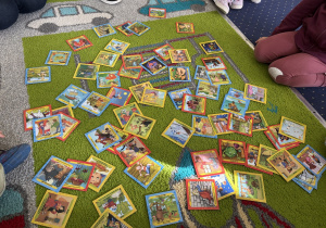 Na dywanie leżą obrazki przedstawiające dziecięce bajki.