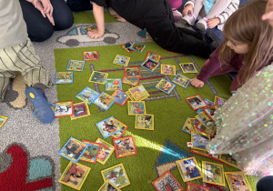 Na dywanie leżą obrazki przedstawiające dziecięce bajki.