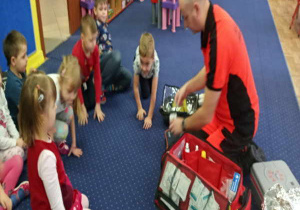 Dzieci i ratownik oglądają torbę ratownika.