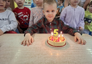 Chłopiec siedzi przed tortem.