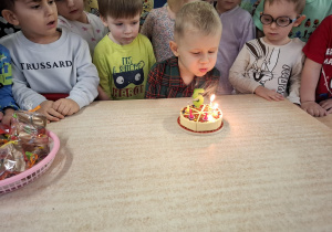 Chłopiec zdmuchuje świeczkę.