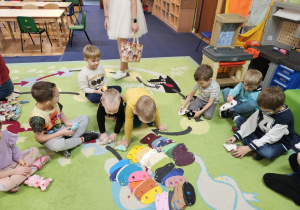 Dzieci siedzą w kole, przed nimi leżą kamizelki dla misia.