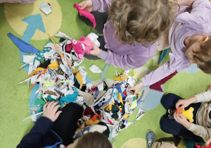 Dzieci siedzą w kole, przed nimi leżą apaszki dla misia.