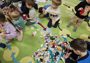 Dzieci siedzą w kole, przed nimi leżą apaszki dla misia.