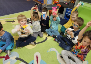 Dzieci siedzą w kole i prezentują swoje misie.