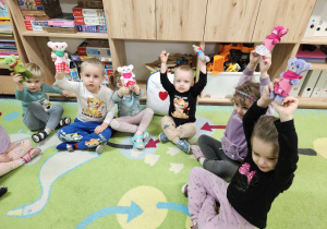 Dzieci siedzą w kole i prezentują swoje misie.