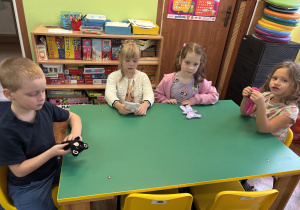 Dzieci siedzą przy stole i oglądają wybranego przez siebie misia.