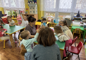 Dzieci siedzą przy stole i prezentują wypchane misia.