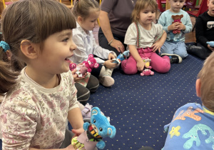 Dzieci siedzą w kole na dywanie i słuchają.