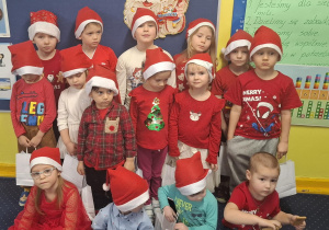 zdjęcie dzieci z grupy 1, dzieci ubrane na czerwono, w czapkach Mikołaja
