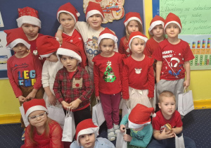 zdjęcie dzieci z grupy 1, dzieci ubrane na czerwono, w czapkach Mikołaja