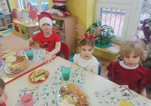dzieci siedzą przy stolikach, jedzą smakołyki