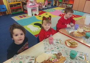 dzieci siedzą przy stolikach, jedzą smakołyki