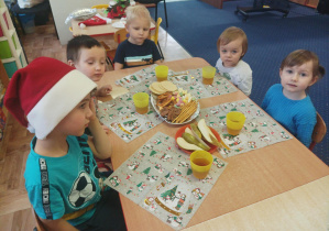 dzieci siedzą przy stolikach, jedzą smakołyki