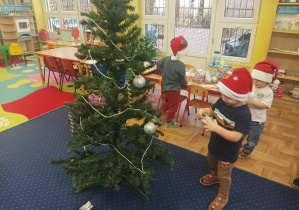 dziewczęta i chłopcy ubierają choinkę